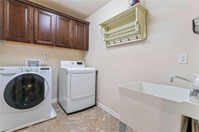 washroom featuring cabinet space, baseboards, a sink, and independent washer and dryer