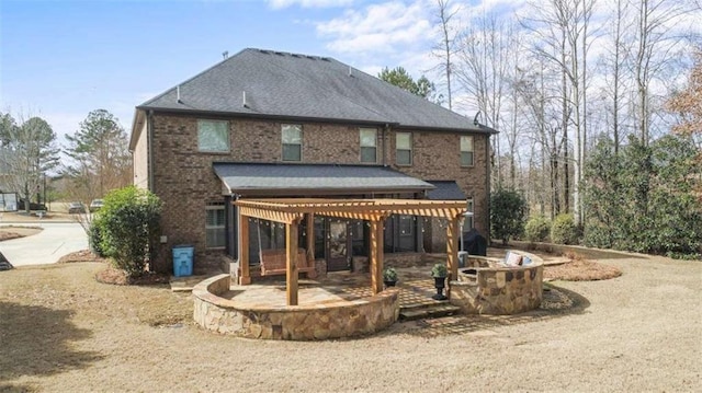 rear view of house featuring brick siding, a patio, and a fire pit