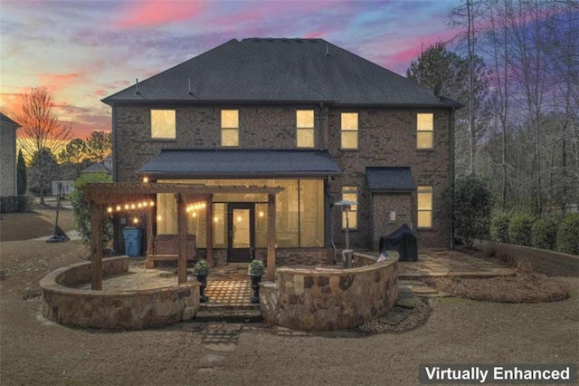 rear view of property with brick siding, a shingled roof, and a patio