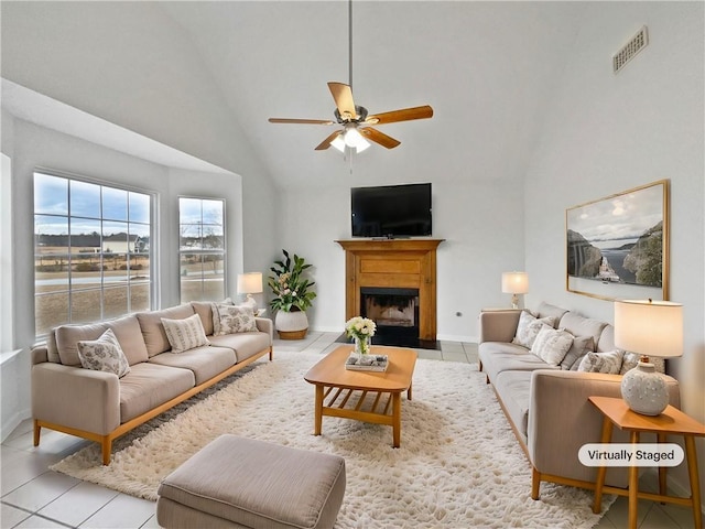 tiled living room with ceiling fan and high vaulted ceiling