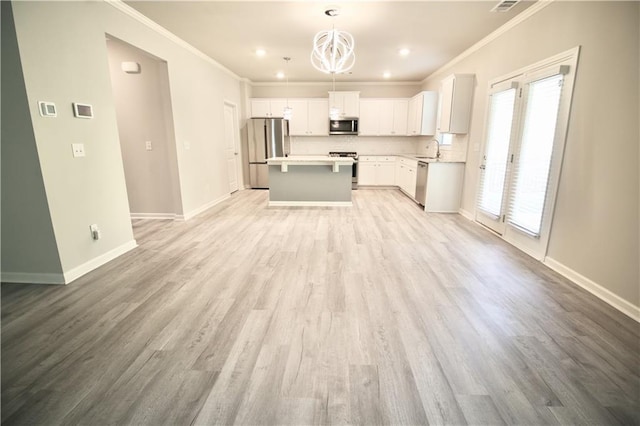 243 Hummingbird Trl, Dallas, GA 30132 - kitchen featuring appliances with stainless steel finishes, crown molding, a center island, light countertops, and white cabinetry