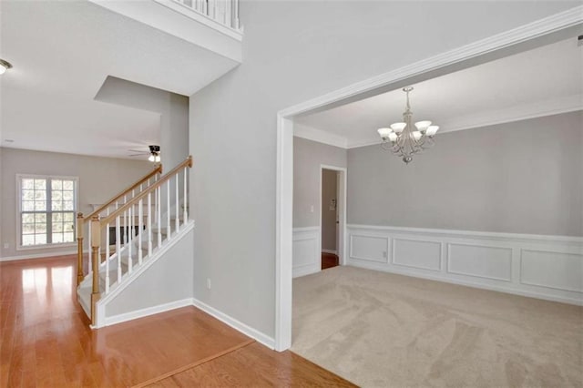 staircase featuring ornamental molding, carpet flooring, a decorative wall, and wood finished floors