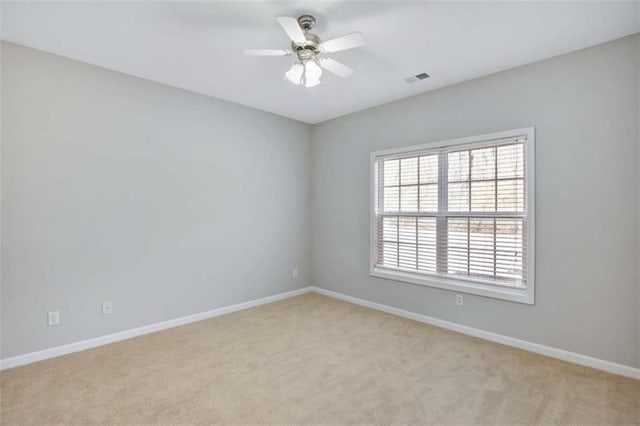 unfurnished room with visible vents, ceiling fan, light carpet, and baseboards