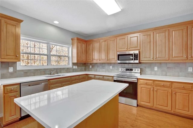 kitchen with appliances with stainless steel finishes, light countertops, a sink, and backsplash