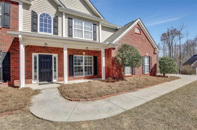 traditional home featuring a porch and brick siding