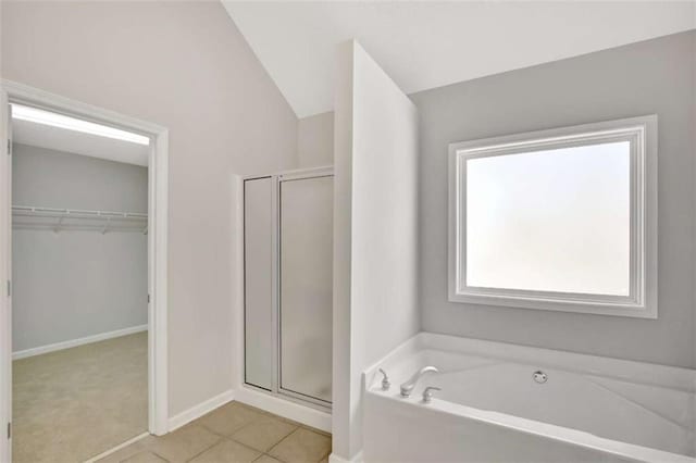 bathroom featuring a stall shower, baseboards, tile patterned floors, a garden tub, and a walk in closet