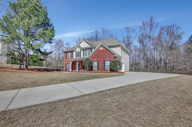 view of front facade featuring a front lawn, concrete driveway, and brick siding