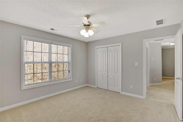 unfurnished bedroom featuring light carpet, baseboards, visible vents, and attic access