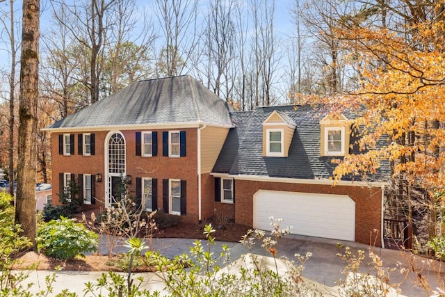 colonial home featuring a garage, concrete driveway, and brick siding