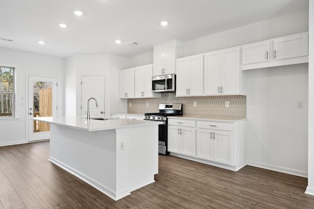 kitchen with white cabinets, appliances with stainless steel finishes, and a kitchen island with sink