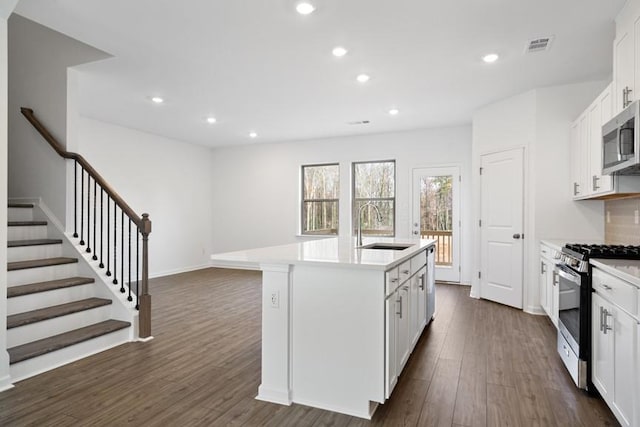 kitchen featuring a center island with sink, sink, stainless steel appliances, white cabinets, and dark hardwood / wood-style flooring