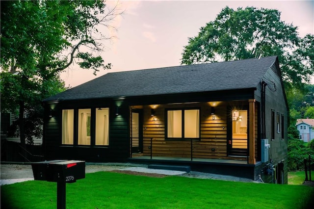 view of front of house with roof with shingles and a front lawn