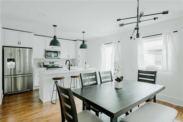 dining area featuring light wood finished floors and baseboards