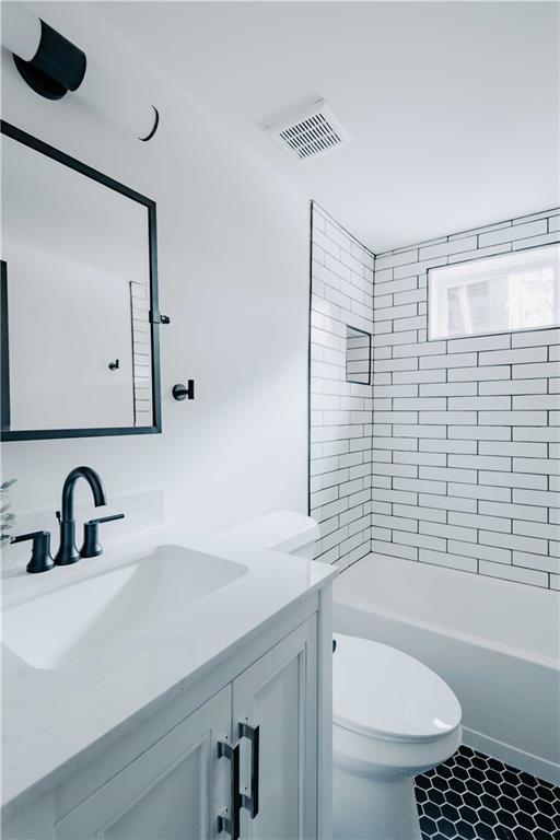 full bath featuring vanity, toilet,  shower combination, and tile patterned flooring