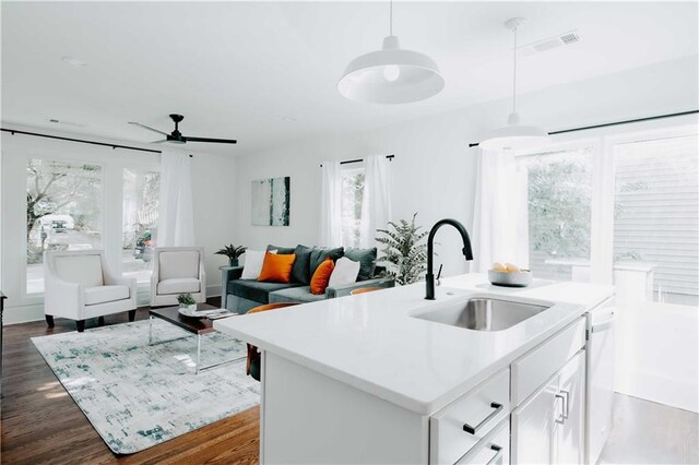 kitchen with a sink, light countertops, decorative light fixtures, white cabinetry, and open floor plan