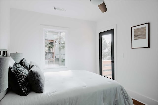 bedroom featuring multiple windows, baseboards, a ceiling fan, and wood finished floors