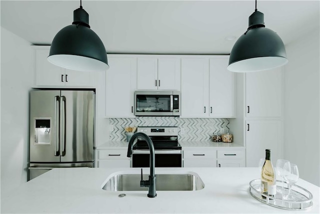 kitchen with stainless steel appliances, light countertops, decorative light fixtures, and white cabinetry