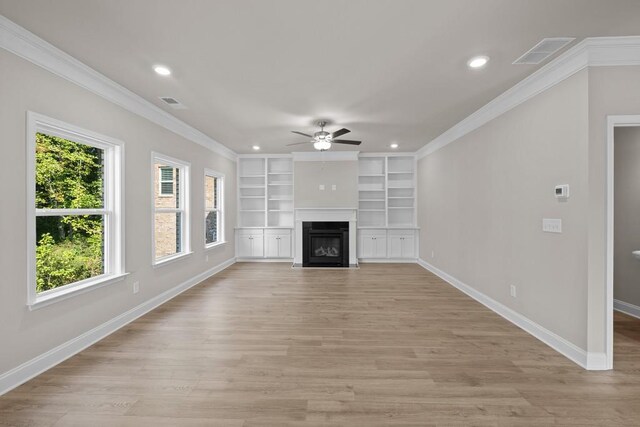 unfurnished living room with built in features, ornamental molding, and a wealth of natural light