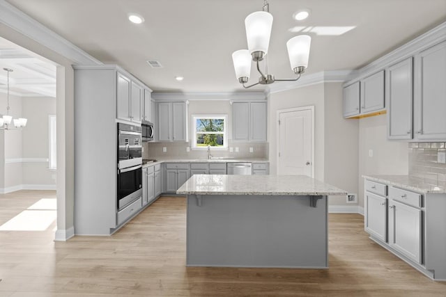 kitchen featuring decorative backsplash, stainless steel appliances, a notable chandelier, and gray cabinetry