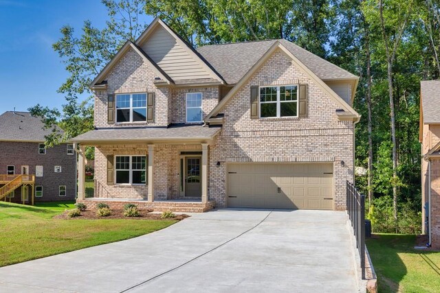 view of front of property featuring covered porch, a garage, and a front yard