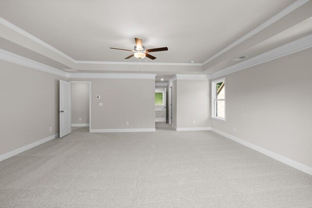 spare room with a raised ceiling, ceiling fan, light carpet, and ornamental molding