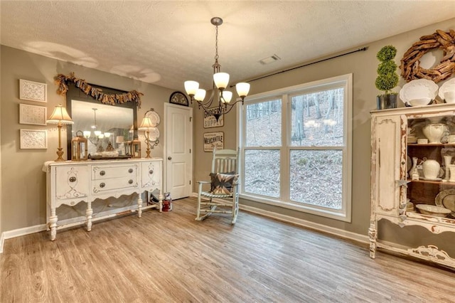 dining room with hardwood / wood-style floors, a textured ceiling, and a notable chandelier