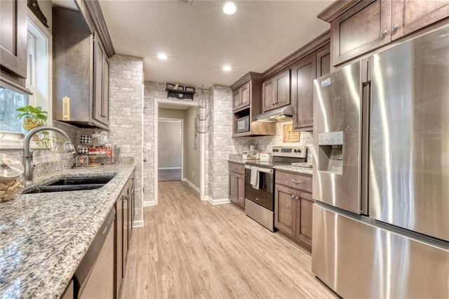 kitchen featuring tasteful backsplash, sink, light hardwood / wood-style floors, stainless steel appliances, and light stone countertops