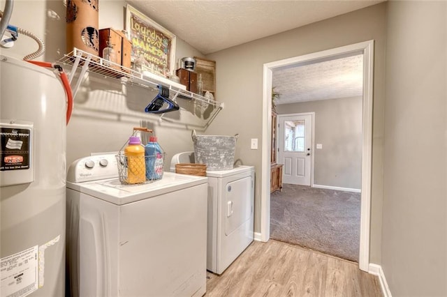 clothes washing area featuring separate washer and dryer, electric water heater, a textured ceiling, and light hardwood / wood-style flooring