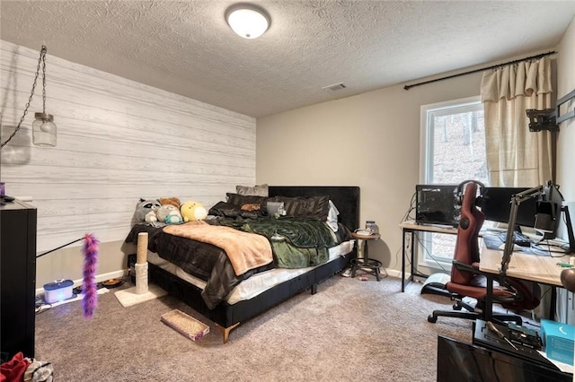 bedroom featuring a textured ceiling, carpet, and wood walls