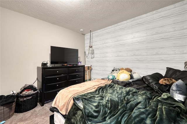 bedroom featuring wooden walls, light colored carpet, and a textured ceiling