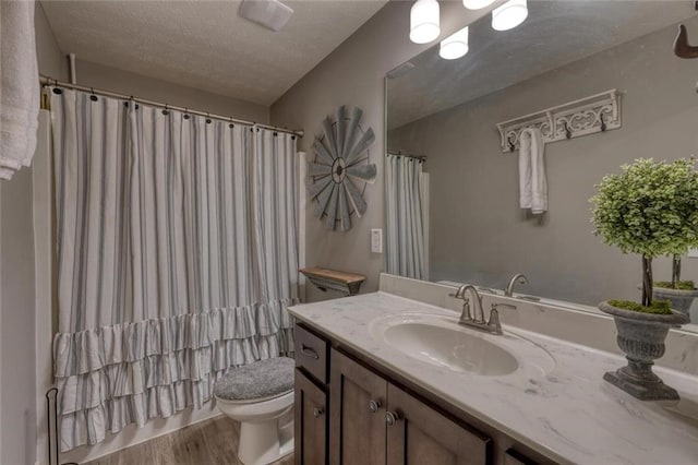 bathroom with hardwood / wood-style flooring, vanity, toilet, and a textured ceiling