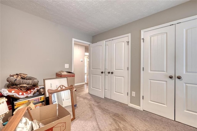 carpeted bedroom featuring multiple closets and a textured ceiling