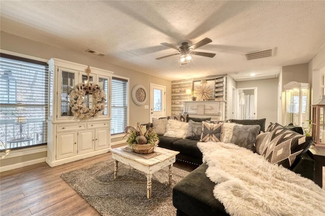 living room featuring ceiling fan, light hardwood / wood-style flooring, and a textured ceiling