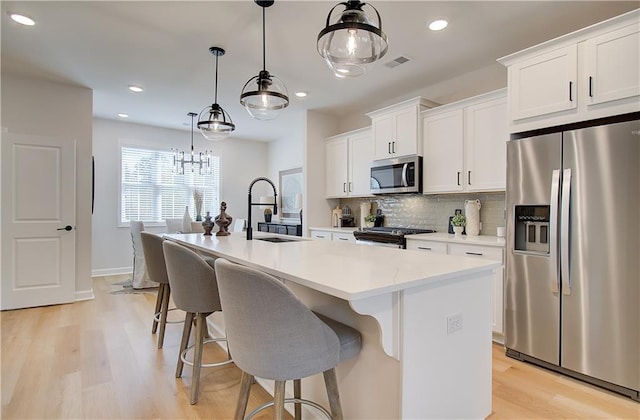 3352 Cranston Ln, Kennesaw, GA 30144 - kitchen featuring appliances with stainless steel finishes, a sink, light wood-type flooring, a center island with sink, and backsplash