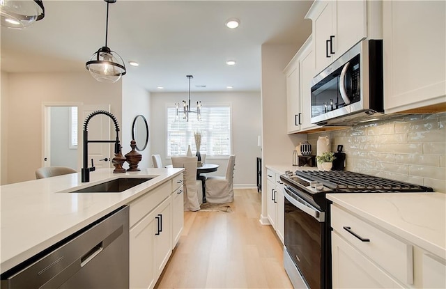 3352 Cranston Ln, Kennesaw, GA 30144 - kitchen with stainless steel appliances, a sink, decorative light fixtures, tasteful backsplash, and light wood-type flooring