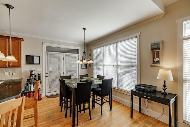 dining room with crown molding, light wood-style flooring, and baseboards