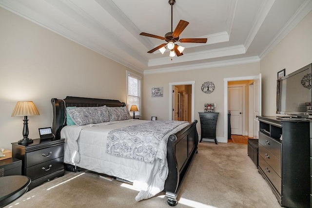 bedroom with light carpet, a tray ceiling, a ceiling fan, and crown molding