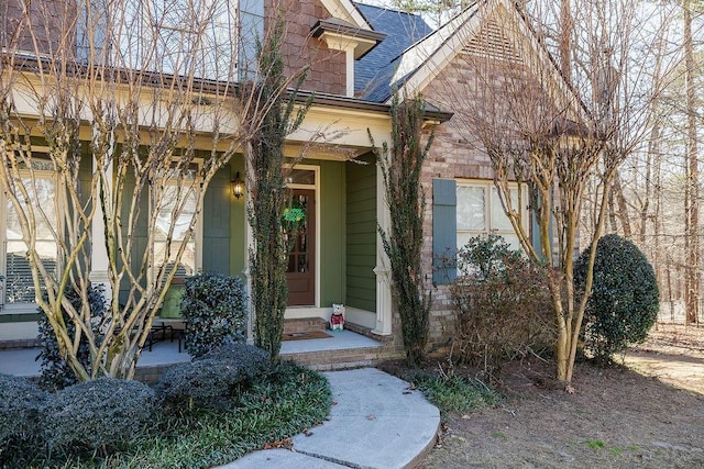 view of exterior entry with a shingled roof