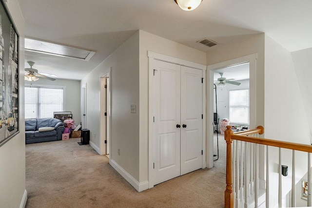 corridor featuring baseboards, visible vents, and light colored carpet