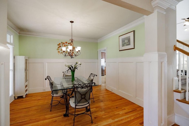 dining space with a chandelier, light wood-style flooring, crown molding, stairway, and ornate columns