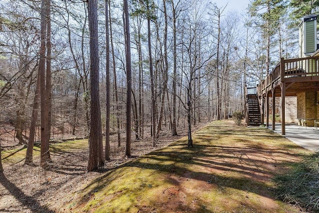 view of yard featuring a wooded view, stairway, and a wooden deck