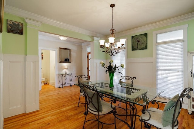 dining room with crown molding, a wainscoted wall, a chandelier, and light wood-style floors