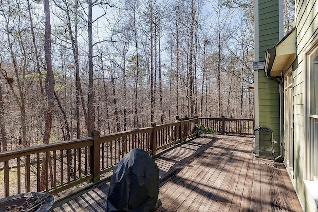 wooden deck with a wooded view and area for grilling