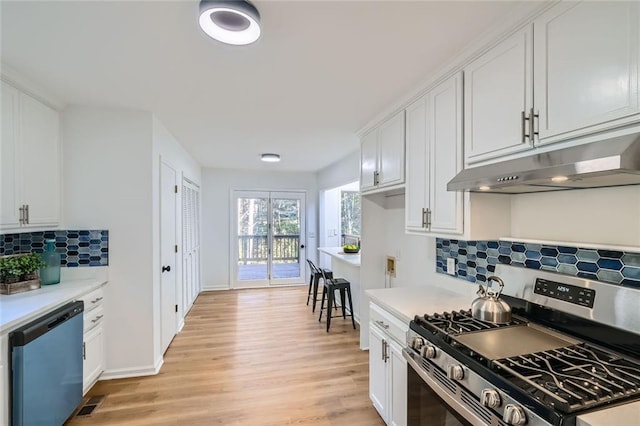 kitchen featuring tasteful backsplash, white cabinetry, stainless steel appliances, and light wood-type flooring