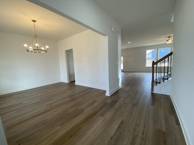 empty room with ceiling fan with notable chandelier and dark hardwood / wood-style floors