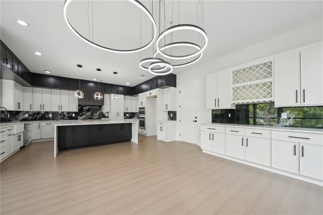 155 Westbrook St, Buford, GA 30518 - kitchen with backsplash, light countertops, white cabinetry, and light wood-style floors