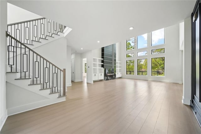 155 Westbrook St, Buford, GA 30518 - unfurnished living room featuring wood finished floors, recessed lighting, a towering ceiling, and stairs