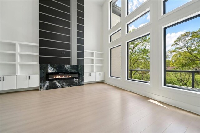 155 Westbrook St, Buford, GA 30518 - unfurnished living room with a high end fireplace, a towering ceiling, built in features, and wood finished floors