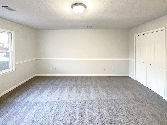 unfurnished bedroom featuring dark carpet, a closet, and a textured ceiling