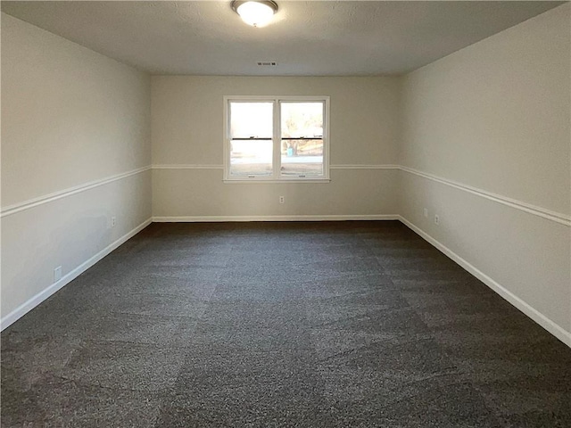 spare room featuring dark colored carpet